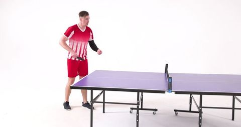 Male table tennis player preparing serve by blue indoor table