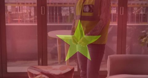 Woman in high-visibility vest by glass doors in urban interior