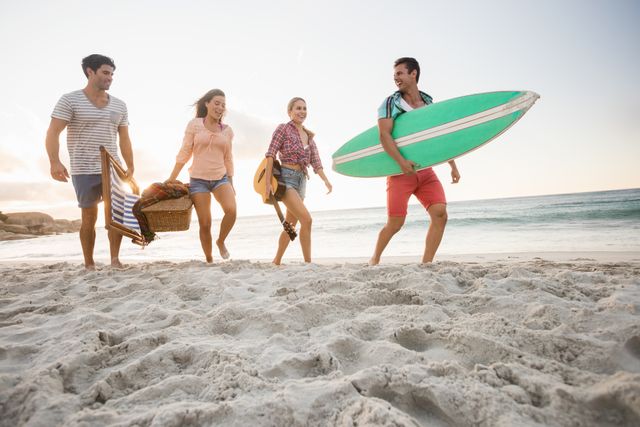 Group of friends walking on sandy beach carrying surfboard and picnic basket. Ideal for use in travel promotions, summer vacation advertisements, lifestyle blogs, and social media posts highlighting outdoor activities and friendship.