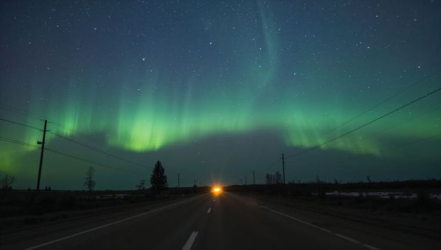 Northern Lights Arching Over Remote Highway, Headlights Guiding Night Drive Under Stars
