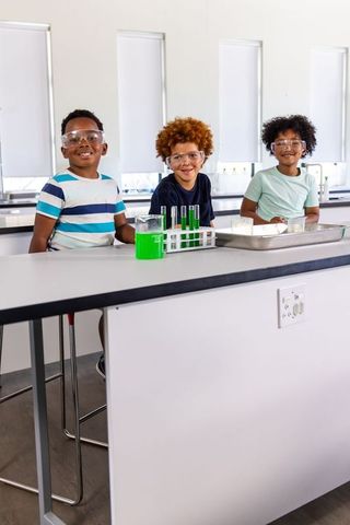 Preteen african american boys conducting chemistry experiment wearing safety goggles