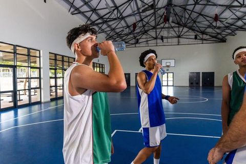Basketball players hydrating during indoor practice session