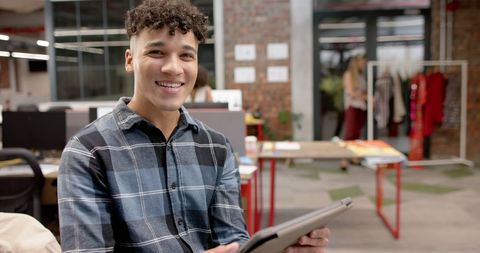 Young Professional Smiling While Holding Tablet in Modern Office - Download Free Stock Images Pikwizard.com