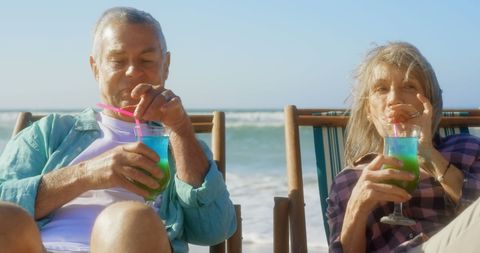 Senior Couple Relaxing with Tropical Cocktails on Beach