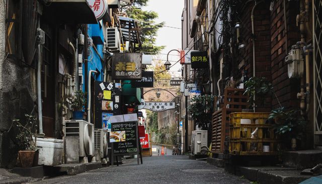 Narrow alleyway in Tokyo lined with shops and restaurants. Japanese cultural and architectural elements prominently displayed. Suitable for depicting urban life, travel destinations, or Japanese street culture.