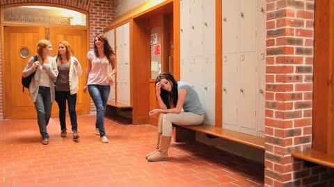 Dejected Student in School Corridor with Passing Classmates