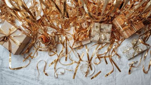 Glistening Gold Ribbons Cascading Over Wrapped Gifts with Dried Rose Flatlay