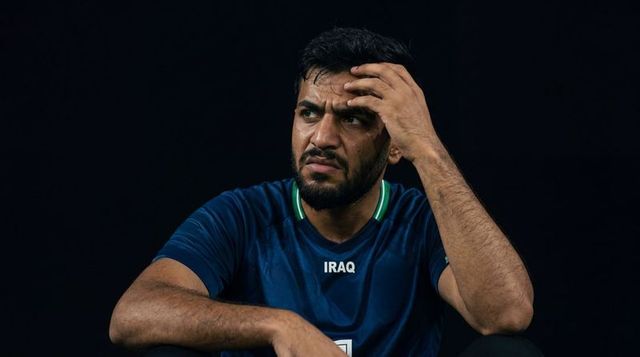 Iraqi football player showing intense focus, frustration, hand on brow in dramatic portrait