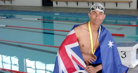 Victorious swimmer celebrating with medal and australian flag poolside
