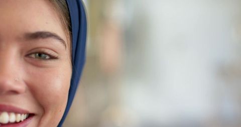 Smiling indian woman wearing blue headscarf and nose stud close-up with soft bokeh
