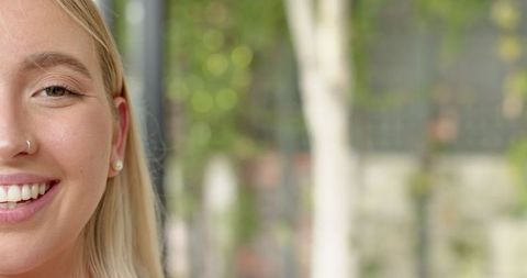 Elegant Woman Smiling Outdoors with Earring and Nose Hoop