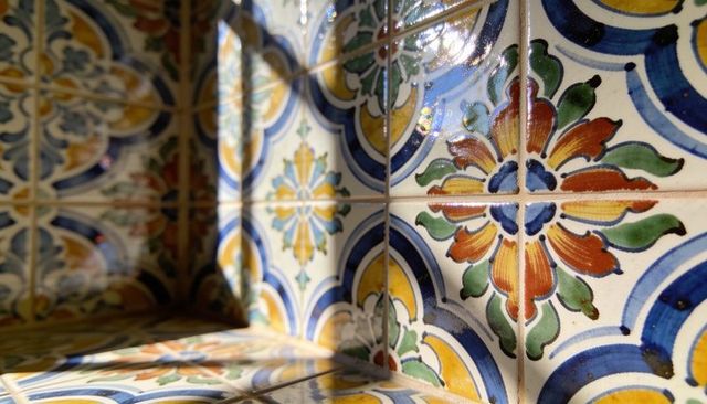 Sunlit glazed floral medallion ceramic tiles casting warm shadows in corner