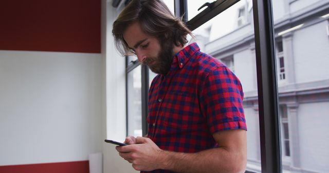 Young Man Texting on Smartphone in Office Setting - Download Free Stock Images Pikwizard.com