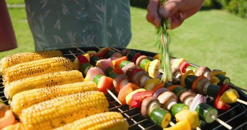 Grilling Vegetable Skewers in Backyard with Fresh Herbs