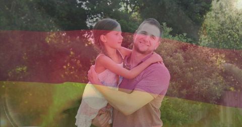 Smiling father holding daughter in sunny backyard with tricolor light overlay warm family moment