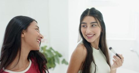 Friends enjoying makeup session in bright modern vanity