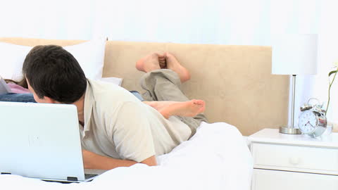 Couple Enjoying Leisure Time in Bedroom with Laptop and Book