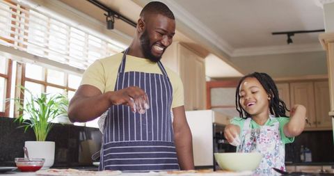 Father and Daughter Enjoying Pizza Preparation Together in Home Kitchen