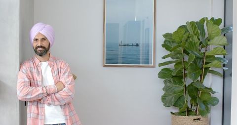 Confident Man in Turban Standing Near Indoor Plant at Home