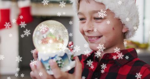 Joyful Child Holding Snow Globe in Festive Setting with Falling Snowflakes - Download Free Stock Images Pikwizard.com