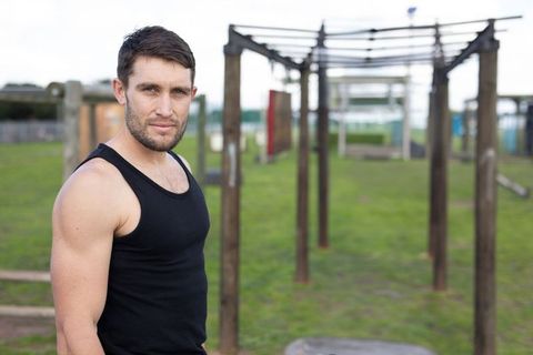 Man in Black Tank Top at Outdoor Fitness Park with Monkey Bars