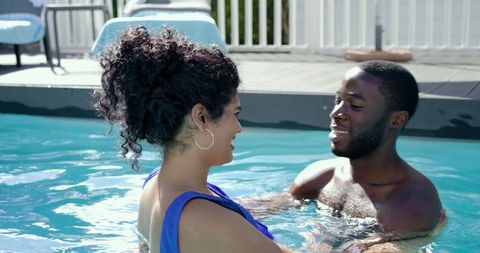 Sunlit poolside couple enjoying relaxed conversation in turquoise water, summer leisure