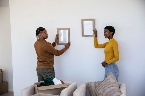 Couple arranging picture frames in new home living room