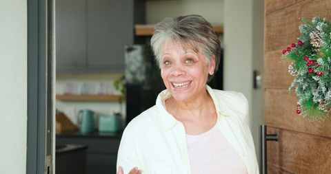 Smiling Senior Woman Welcoming Guest into Festive Kitchen