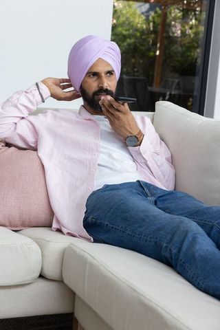 Indian man recording voice message on smartphone in relaxing home setting