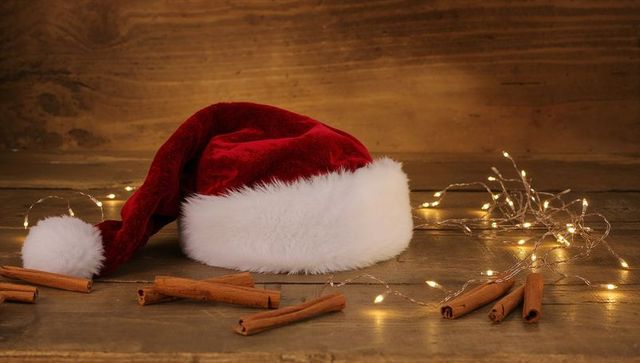 Rustic Santa Hat on Wooden Table with Cinnamon Sticks and Warm Fairy Lights