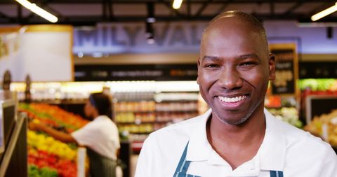 Smiling supermarket employee writing on clipboard