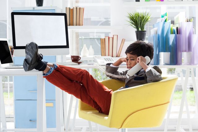 Young Boy in Office Talking on Phone with Feet on Desk - Download Free Stock Images Pikwizard.com