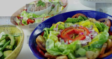 Colorful fresh salad bowls with lettuce, tomatoes, peppers and croutons on white countertop