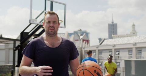 Basketball Player Holding Ball on Outdoor Court in Urban Setting
