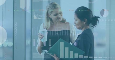 Businesswomen collaborating over reports with data visualization overlays in glass-walled office