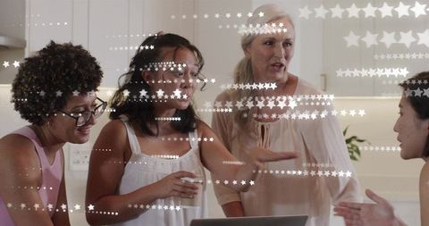 Four Women Collaborating Over Laptop in Bright Kitchen Discussing Ideas Planning Project