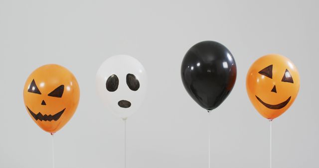 Multiple scary faces printed halloween balloons floating against grey background. halloween holiday and celebration concept