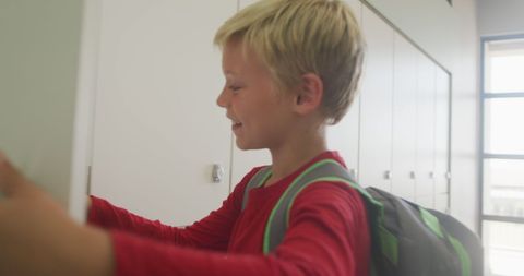 Smiling Boy Closing Locker at School