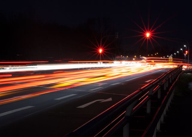 Vibrant long exposure night scene of traffic on highway with light trails creating dynamic motion blur effect. Useful for articles or projects related to urban transportation, speed, nightlife, and modern city infrastructure.