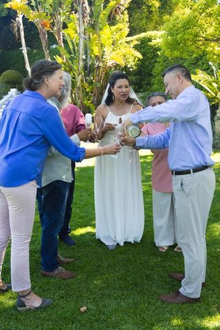 Sunlit backyard wedding celebration featuring bride and guests celebrating champagne toast