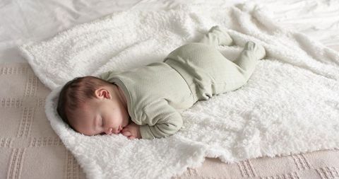Sweet Sleeping Infant in Pale Green Onesie on Soft Bedding