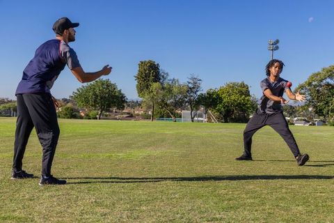 Diverse teammates practicing throw and catch drills on community sports field