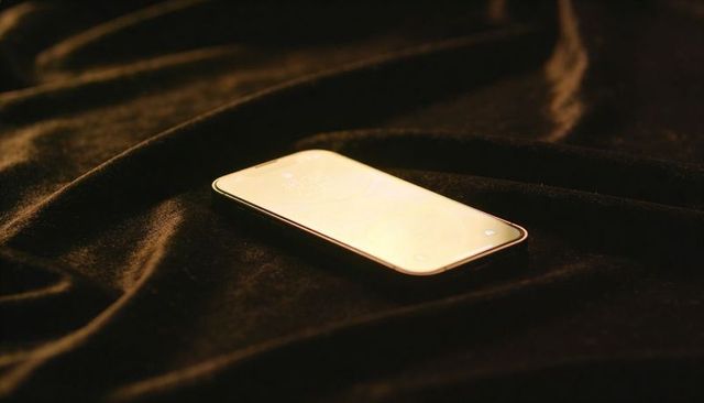 Reflecting modern smartphone glowing on dark velvet fabric with warm golden bezel