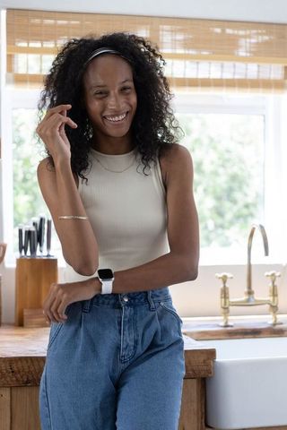 Smiling african american woman leaning on rustic kitchen counter touching hair, lifestyle