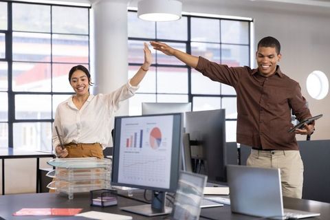 Coworkers High-Fiving in Modern Office for Business Success