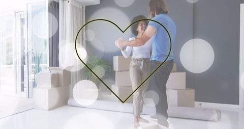 Happy couple dancing among packing boxes in new home