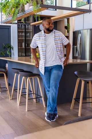 African american man leaning on wood island in modern open-plan kitchen with plants