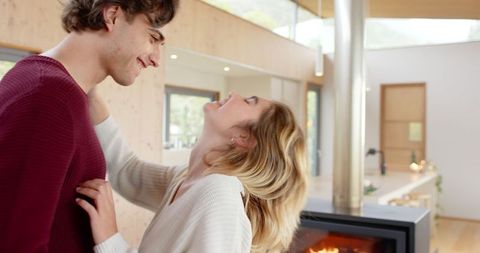 Romantic Couple Embracing Near Fireplace in Modern Living Room