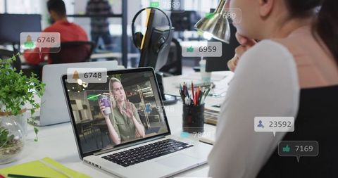 Remote worker watching live reaction stream on laptop with engagement badges in open office