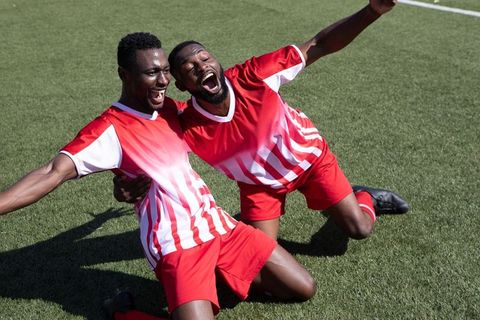 Celebrating teammates in striped jerseys on soccer field